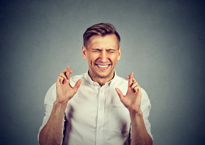 A man crossing his fingers with his eyes closed.