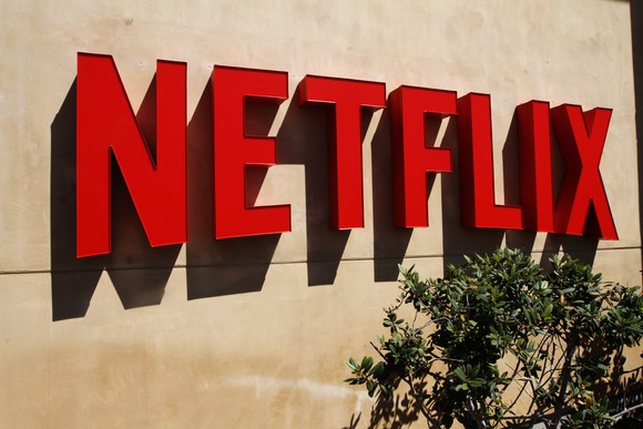 Red Netflix logo on a stucco wall outside the company's headquarters.