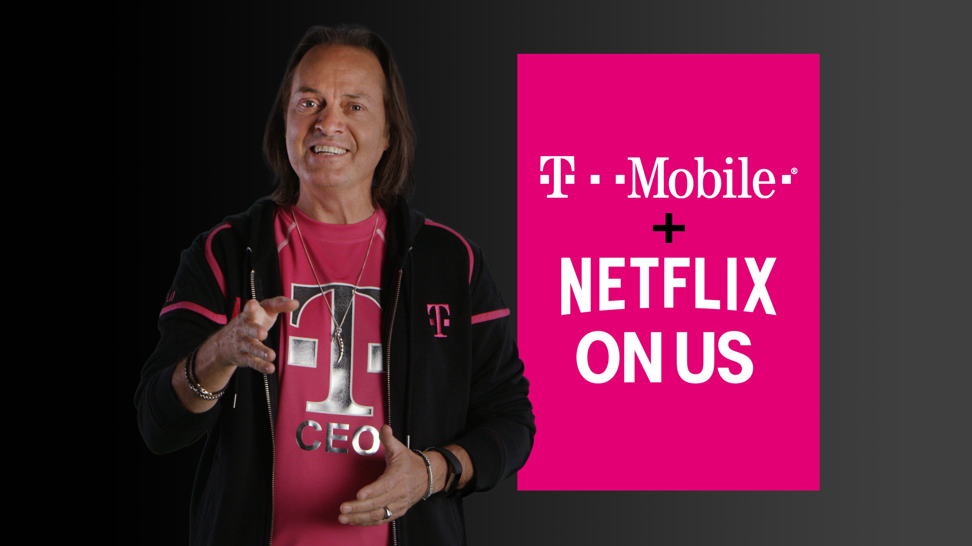 T-Mobile CEO John Legere standing next to a sign that says "T-Mobile plus Netflix on us"