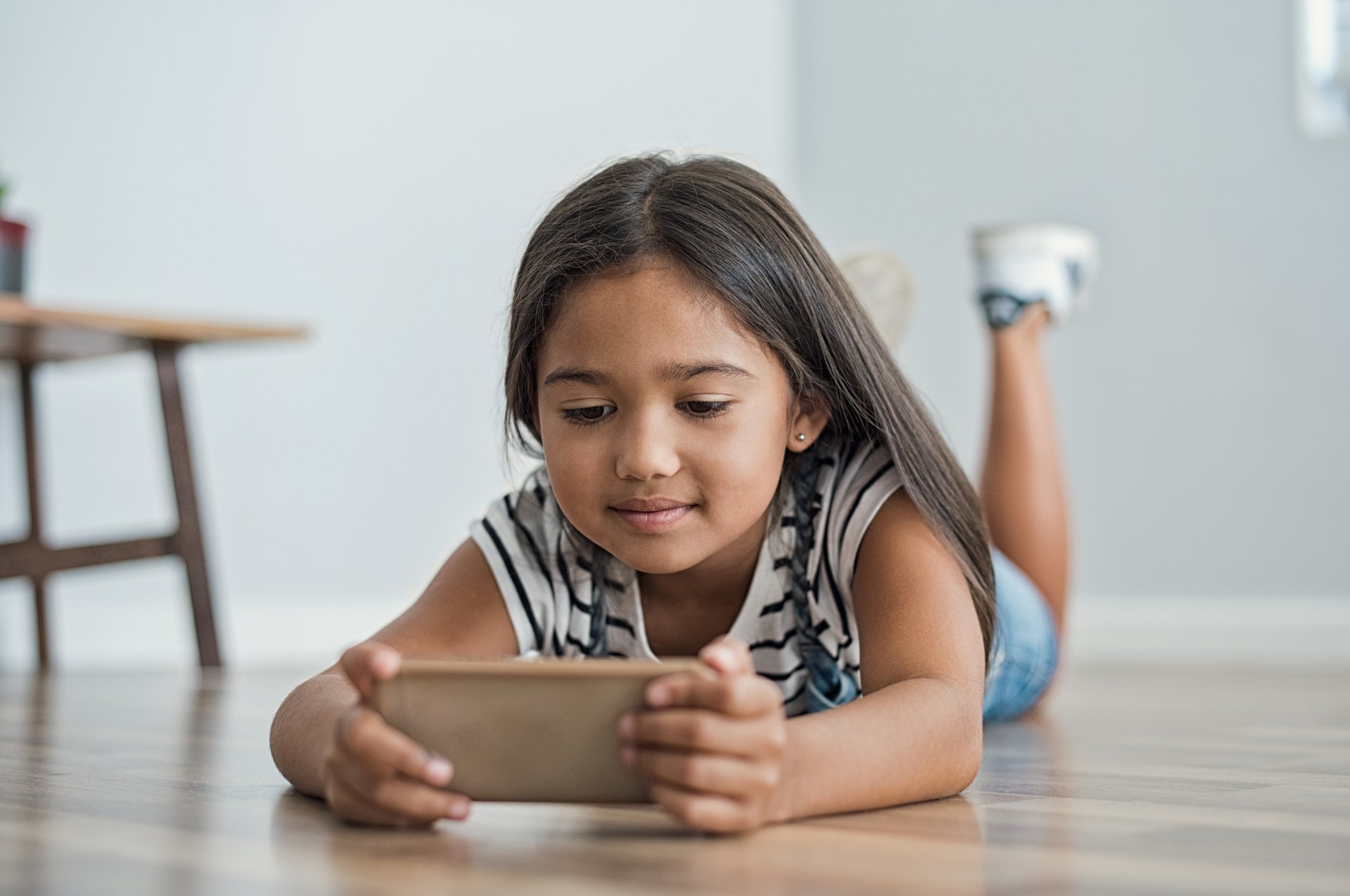 A young girl looks at the screen of a mobile phone.