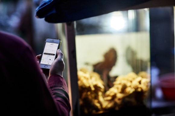 Person looking at smartphone with Uber app open.