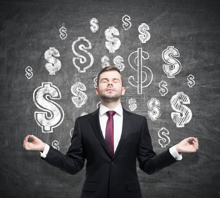 Man meditating in front of dollar signs