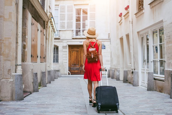 A woman dragging a suitcase on a European street