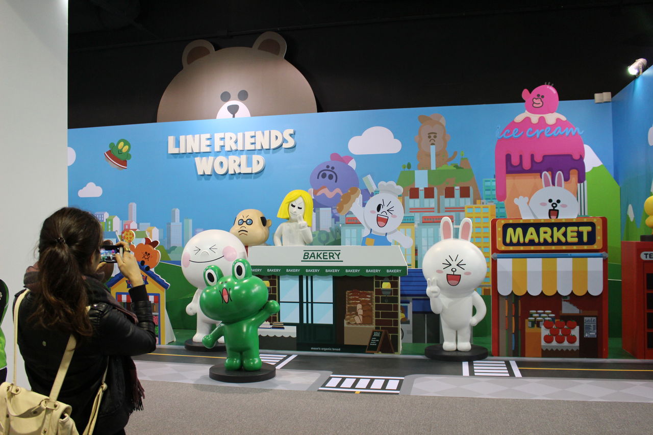 A tourist at the LINE theme park in Taiwan takes a picture of brightly colored cartoon characters.