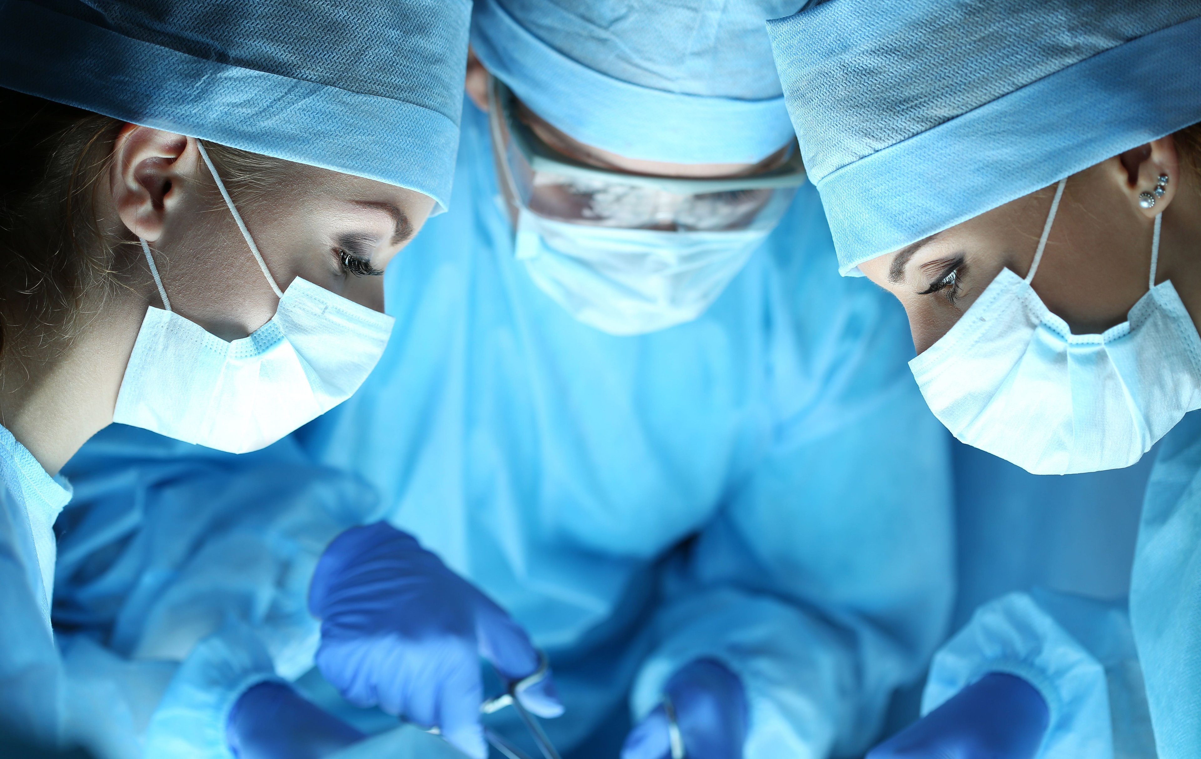 Three surgeons in blue over an operating table