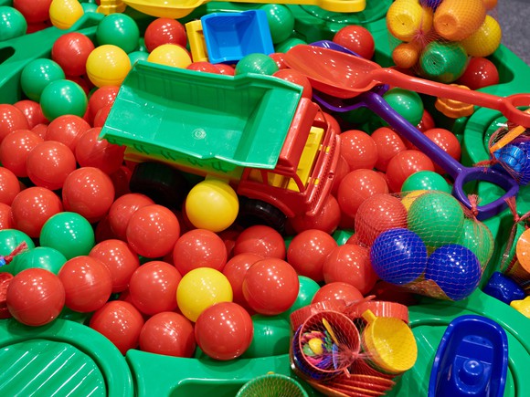 Plastic toy truck, plastic shovels, and other assorted toys in a ball pit. 