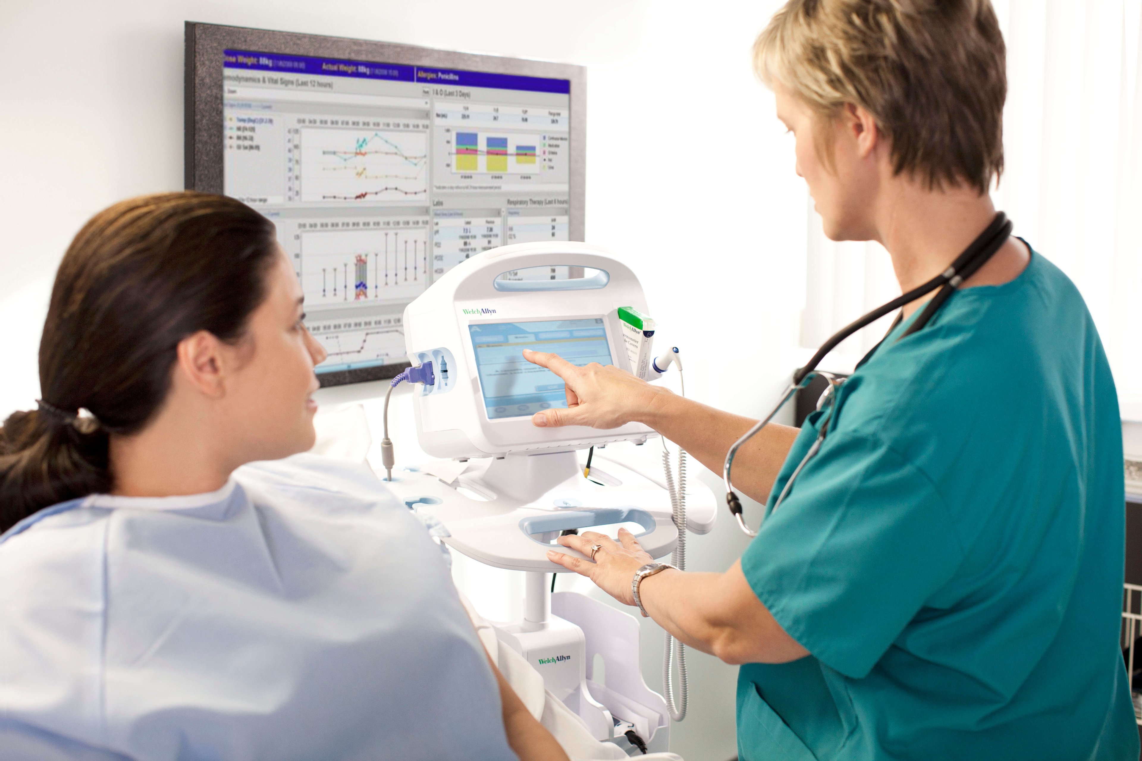 A doctor using a device with a digital screen talking with a patient.