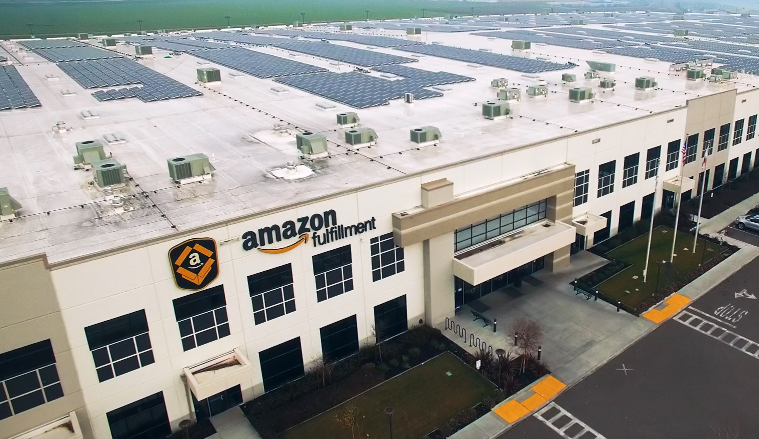 An Amazon fulfillment center, showing off a large roof decked out with hundreds of solar panels.
