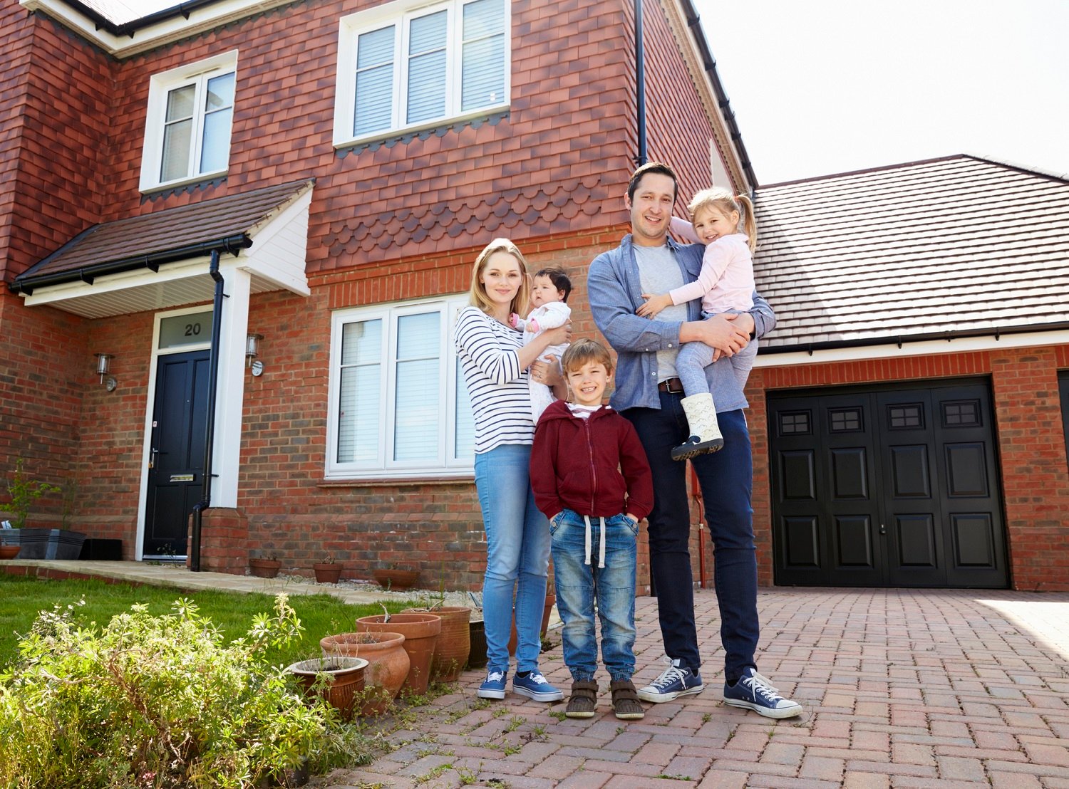 Young family standing in front of their house