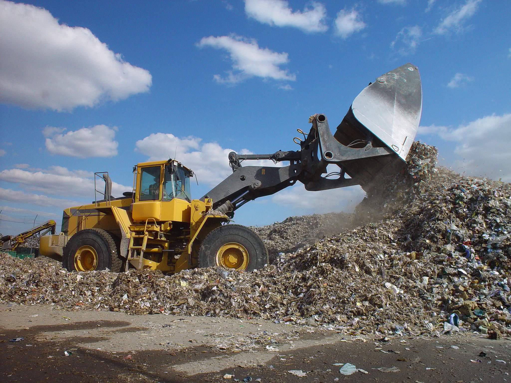 Backhoe loader moving waste in a dump.