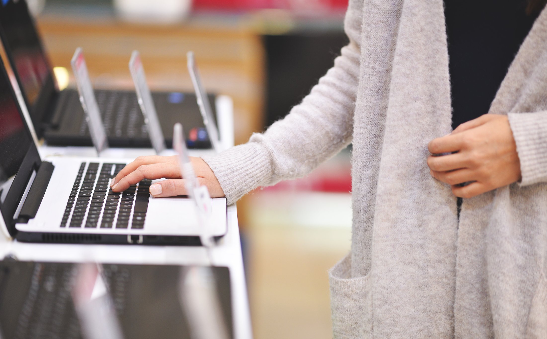 Woman putting her hand on a laptop in a store.