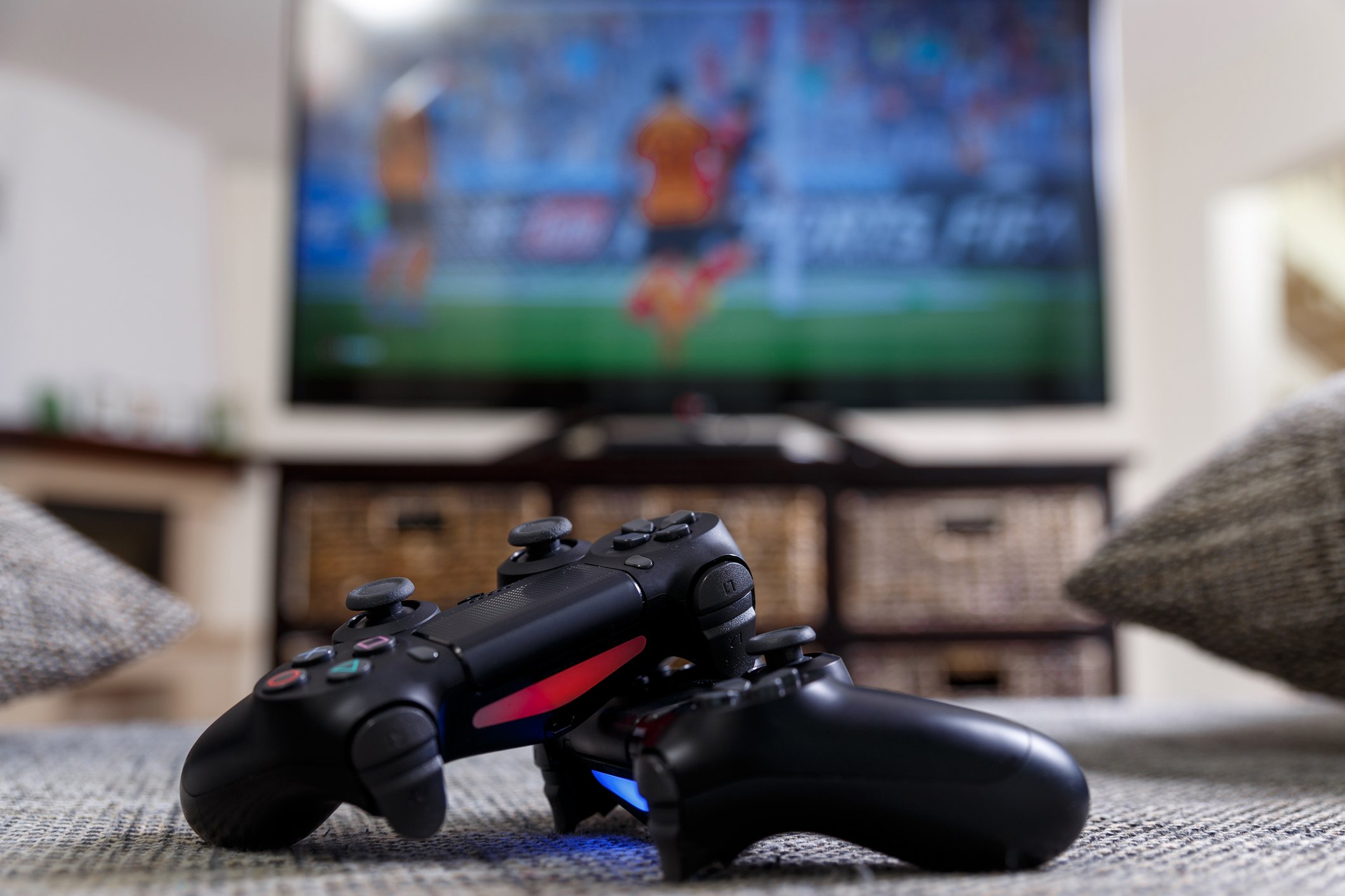 Two PlayStation 4 controllers in front of a television.