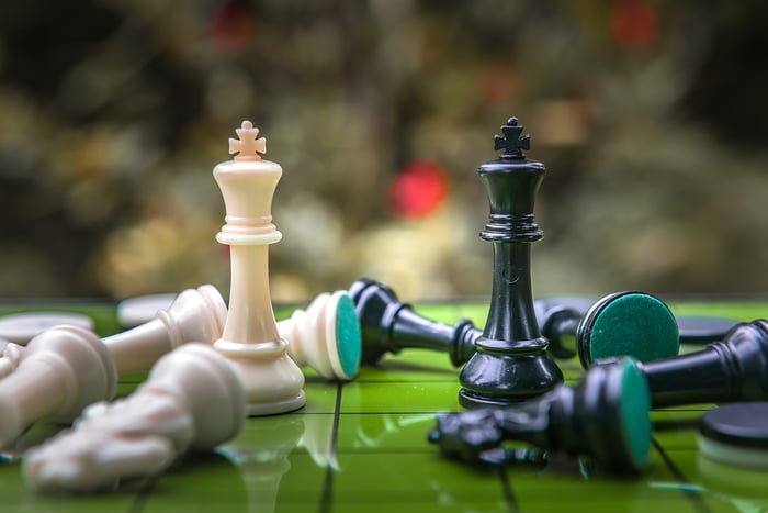Two chess piece kings facing each other while other chess pieces are scattered around them 