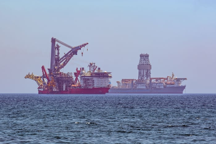 Drill ship and service vessel at sea.