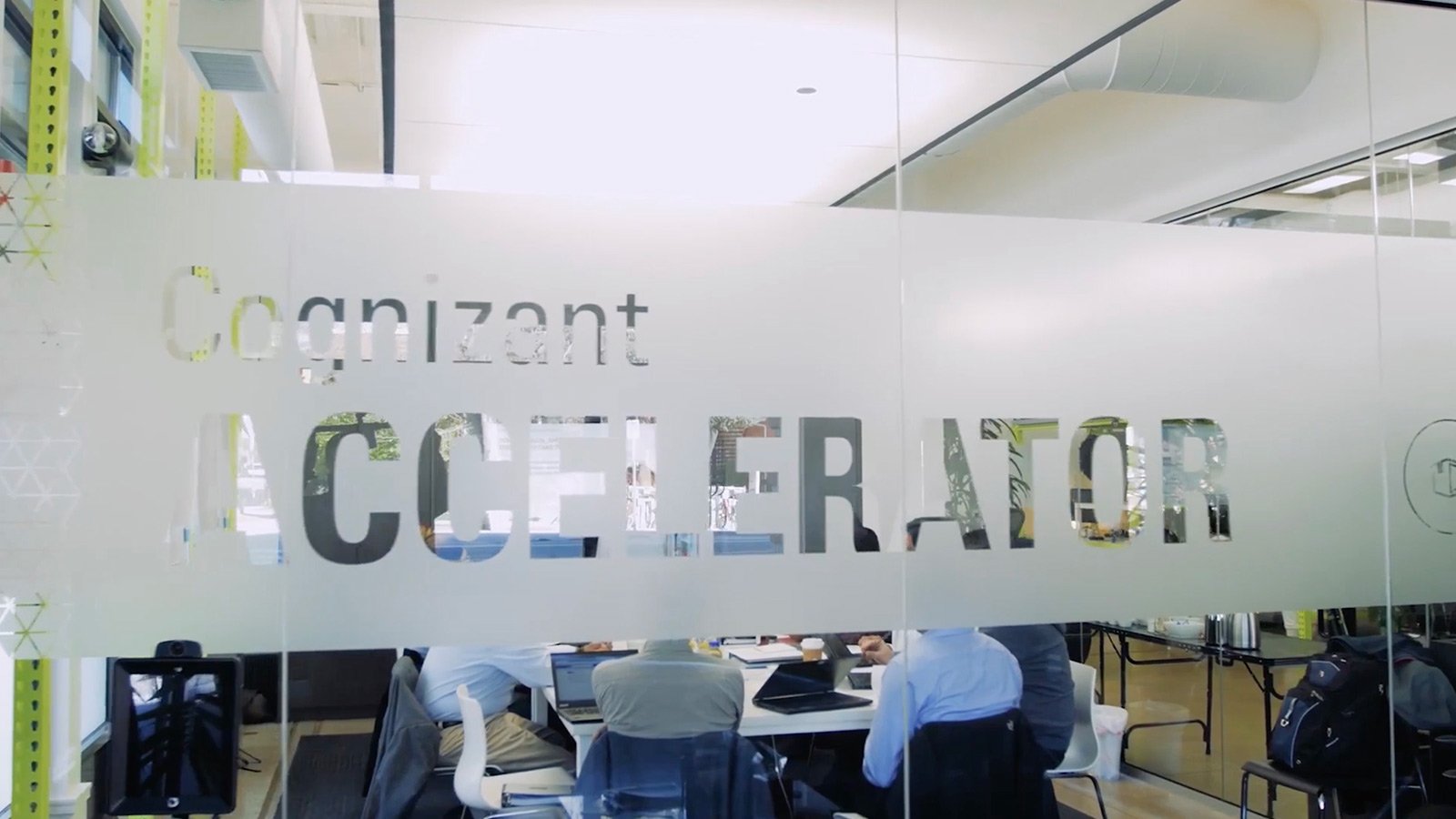 Glass wall with Cognizant Accelerator glazed on its surface, with a conference table beyond.