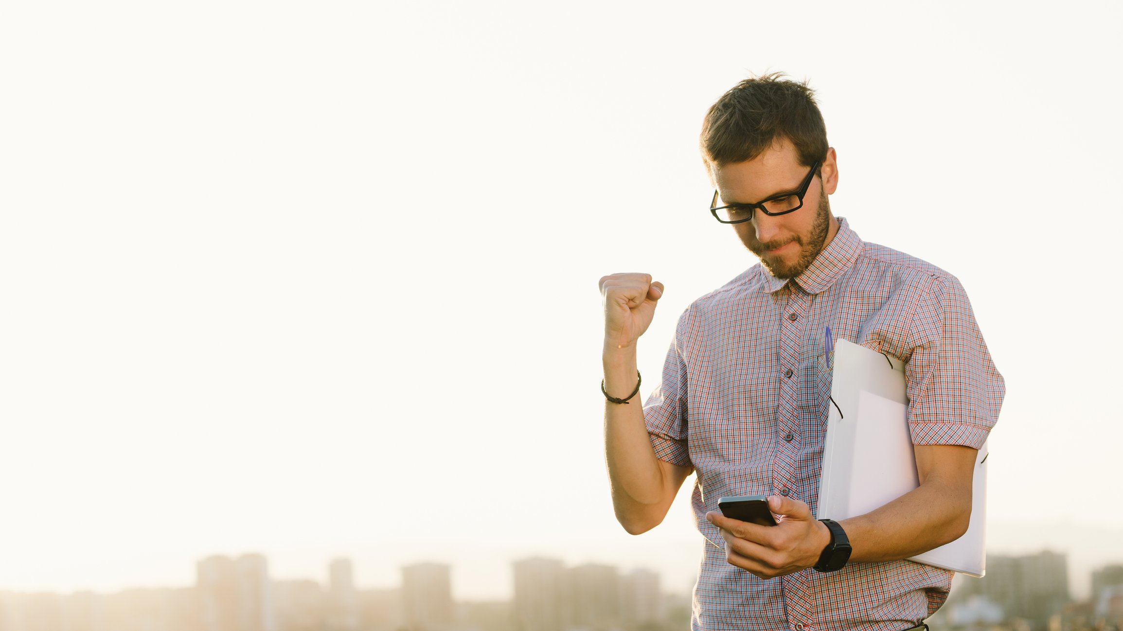 Man holding up fist and looking at phone