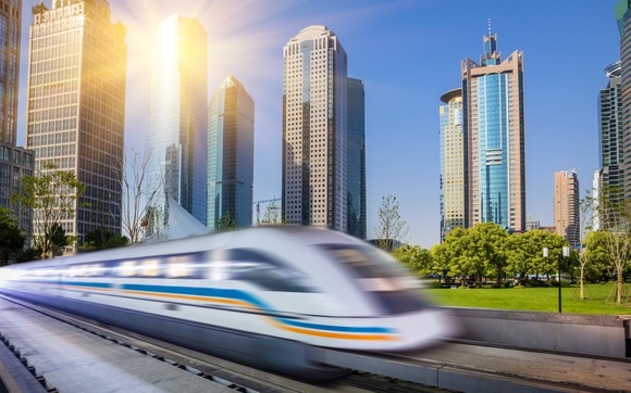 A commuter train in Shanghai passing tall buildings