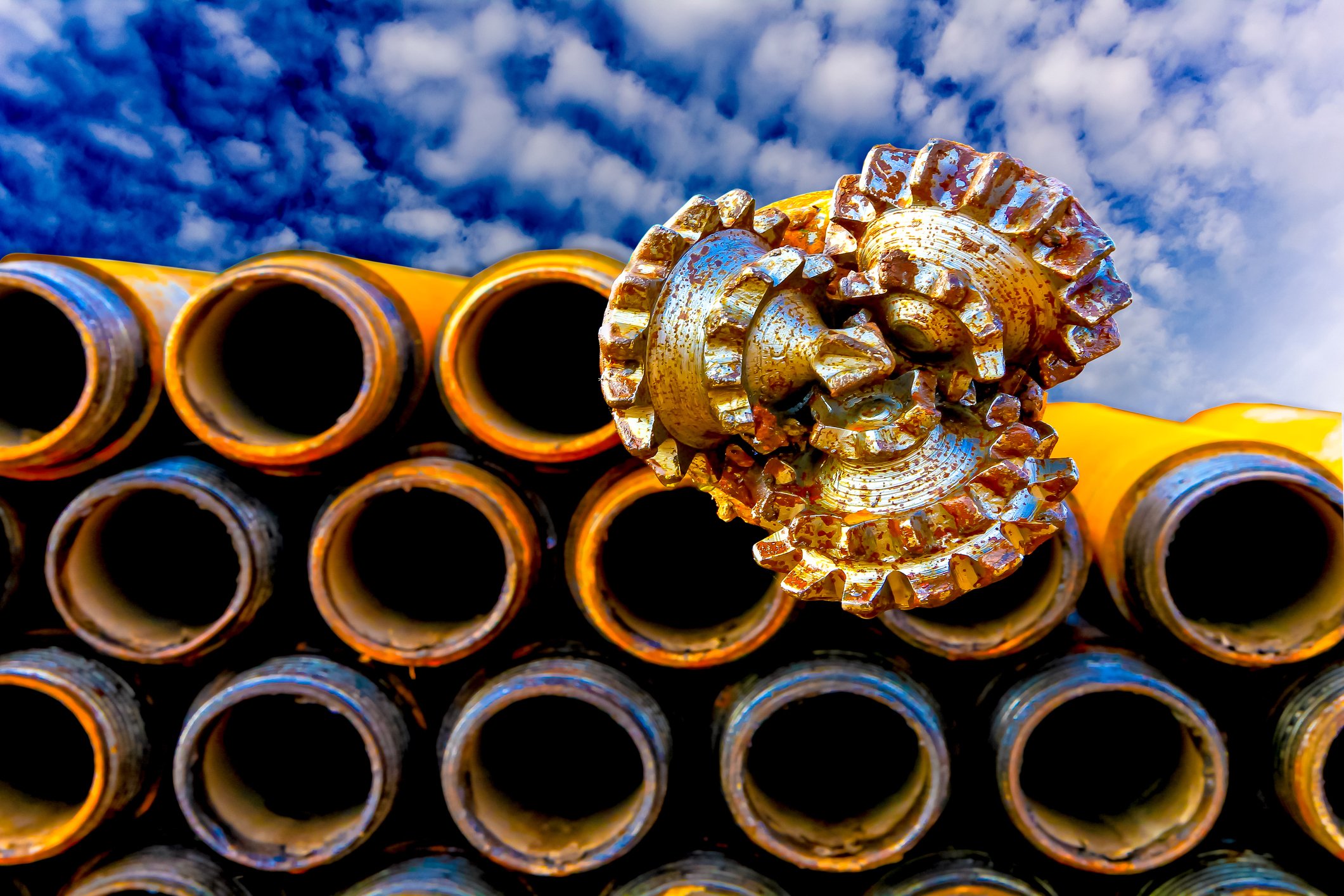 An oil-drill bit sitting atop a stack of large pipes