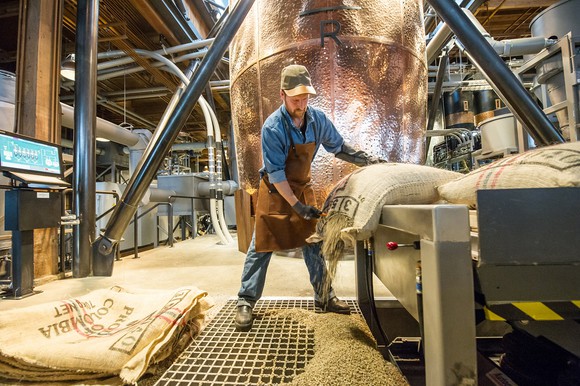 Starbucks employee opening bags of coffee beans.
