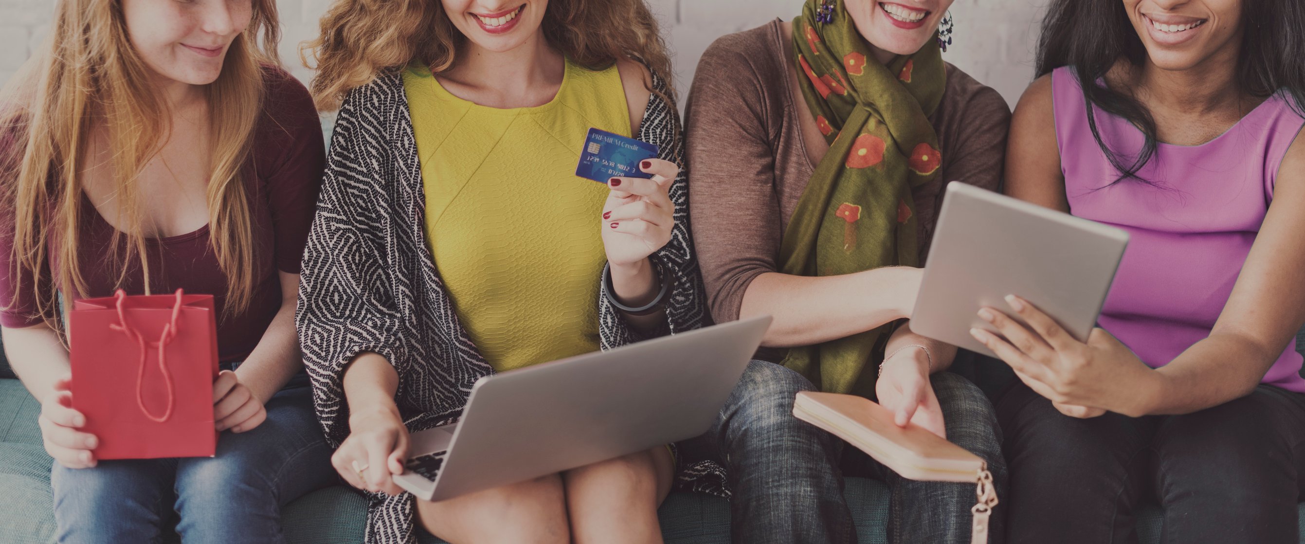 A line of women holding laptops and credit cards