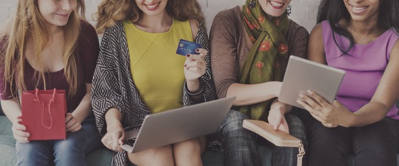 A line of women holding laptops and credit cards