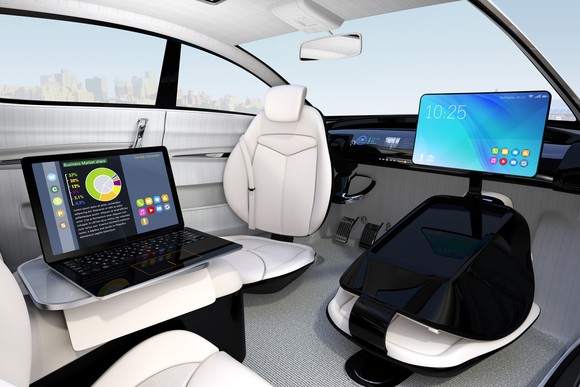 An artist's concept of a driverless car with laptop and computer desk shown inside the vehicle