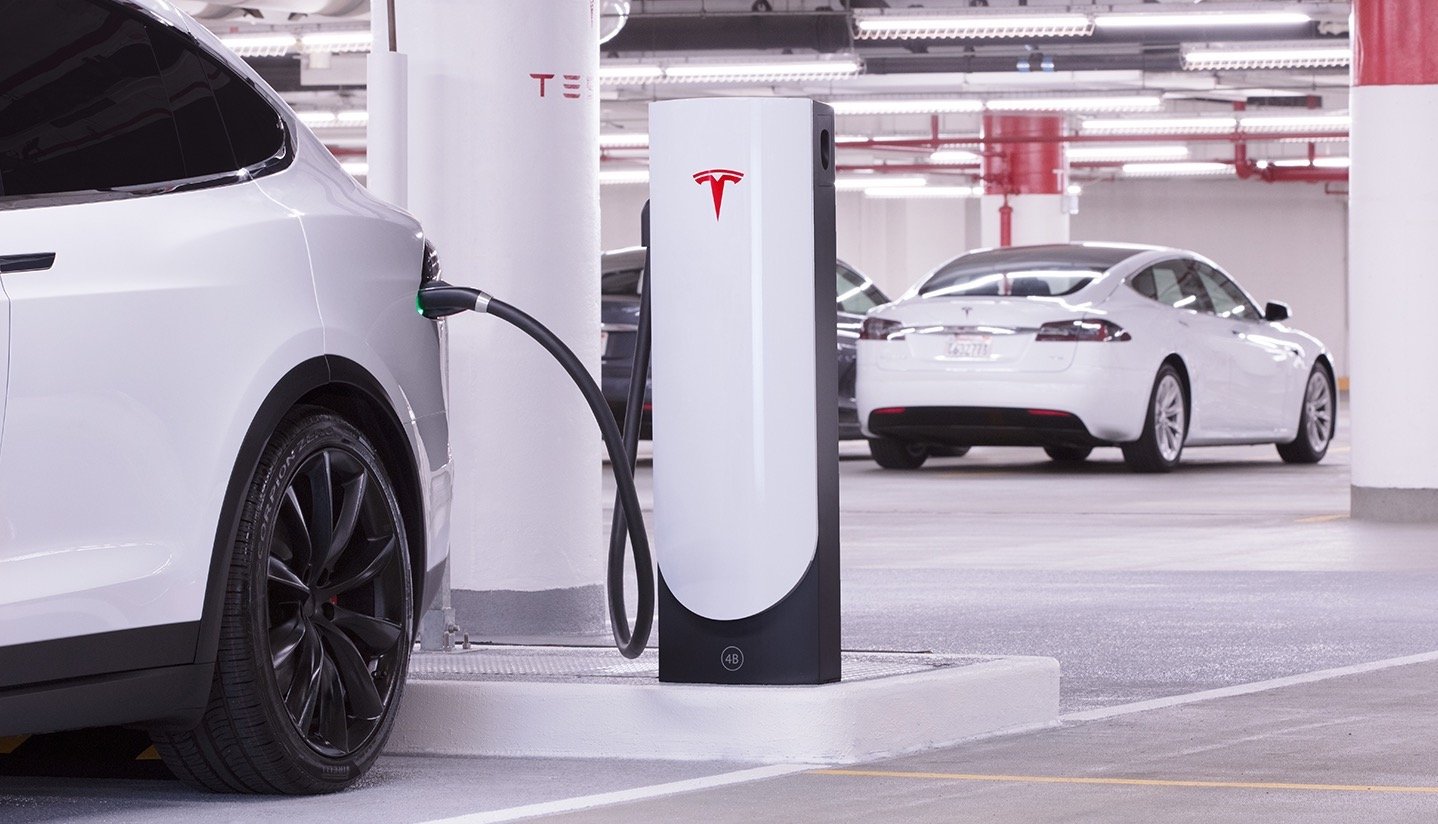 A Tesla Model X is shown at a Supercharger recharging station in a parking garage.
