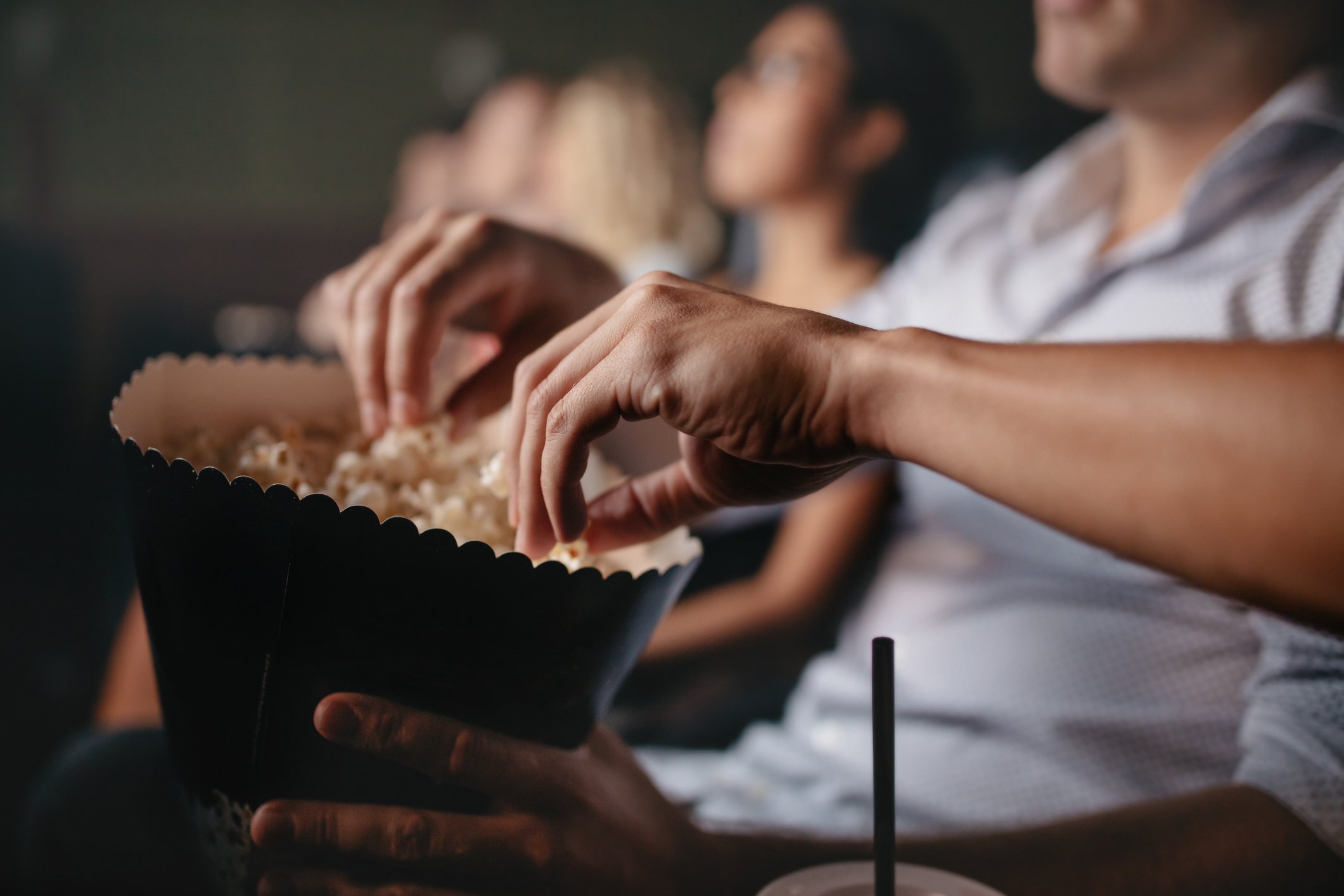 two hands reach into a bag of movie theater popcorn