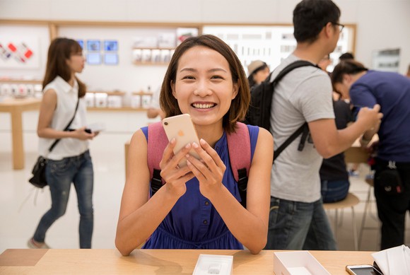 A woman holding a gold iPhone 8 inside of an Apple Store.