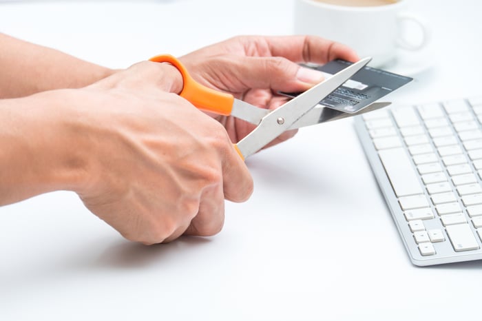 A person cutting a credit card with scissors.