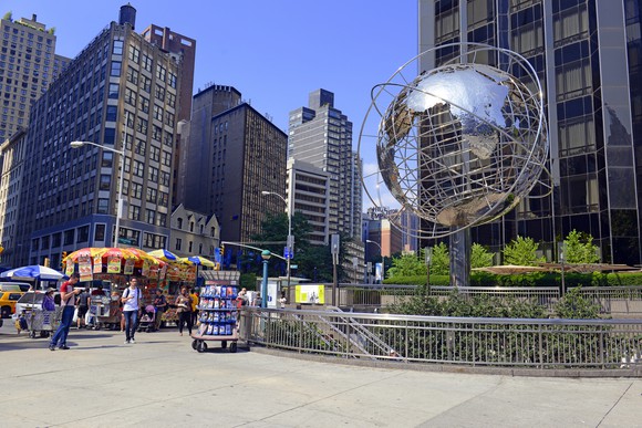 A commercial property complex with street vendors and a metal globe.