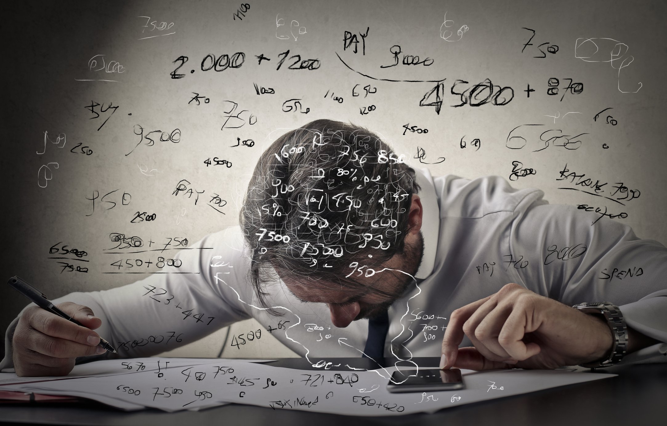 A man hunched over papers calculating numbers.