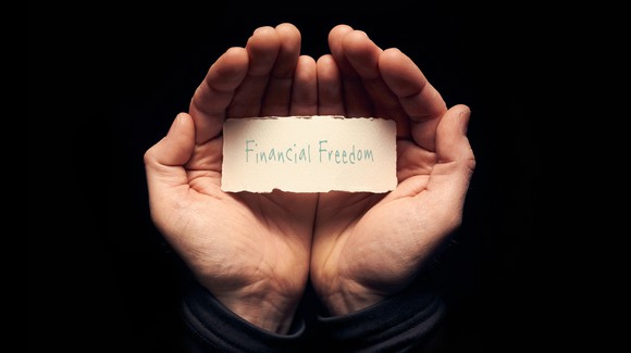 A pair of hands holding a sheet of paper that reads: Financial Freedom