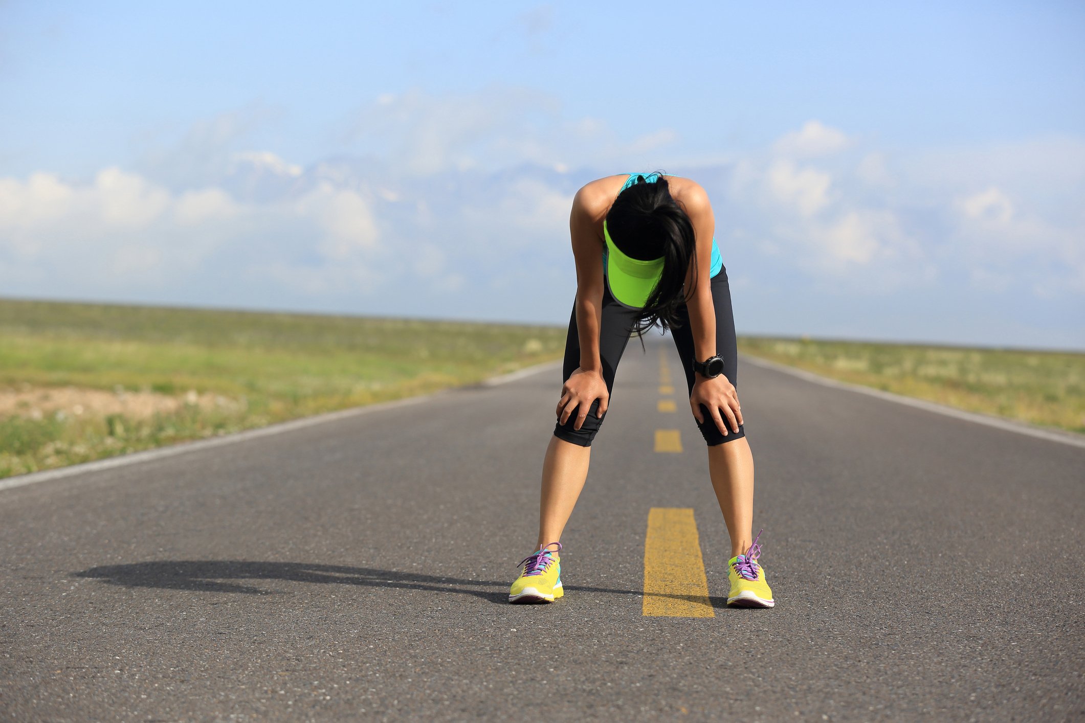 An exhausted runner catching her breath on a road.