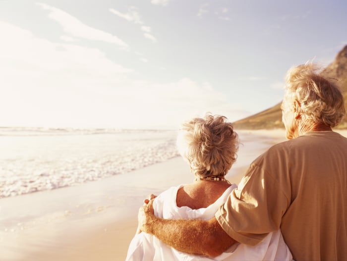 Elderly couple walking on beach.