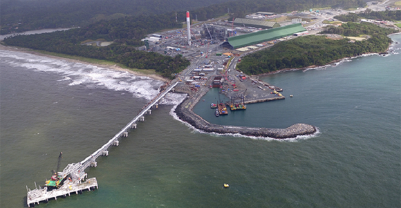 Production facility on a coast line with a shipping pier and dock extending into the water.