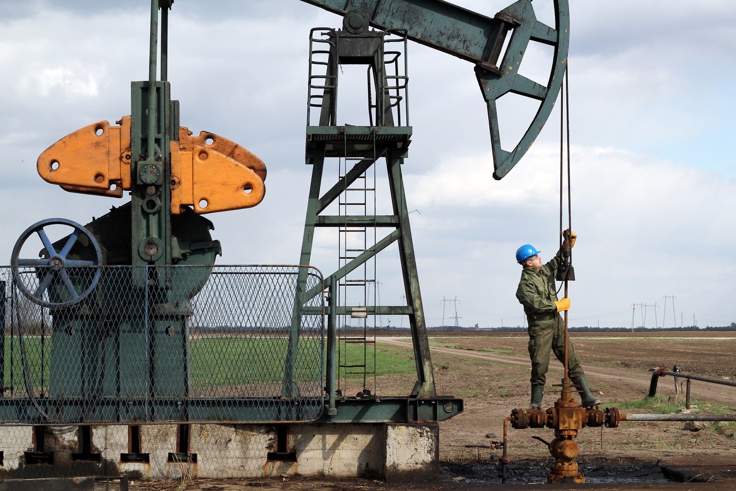 Oil field worker standing on a pump jack.