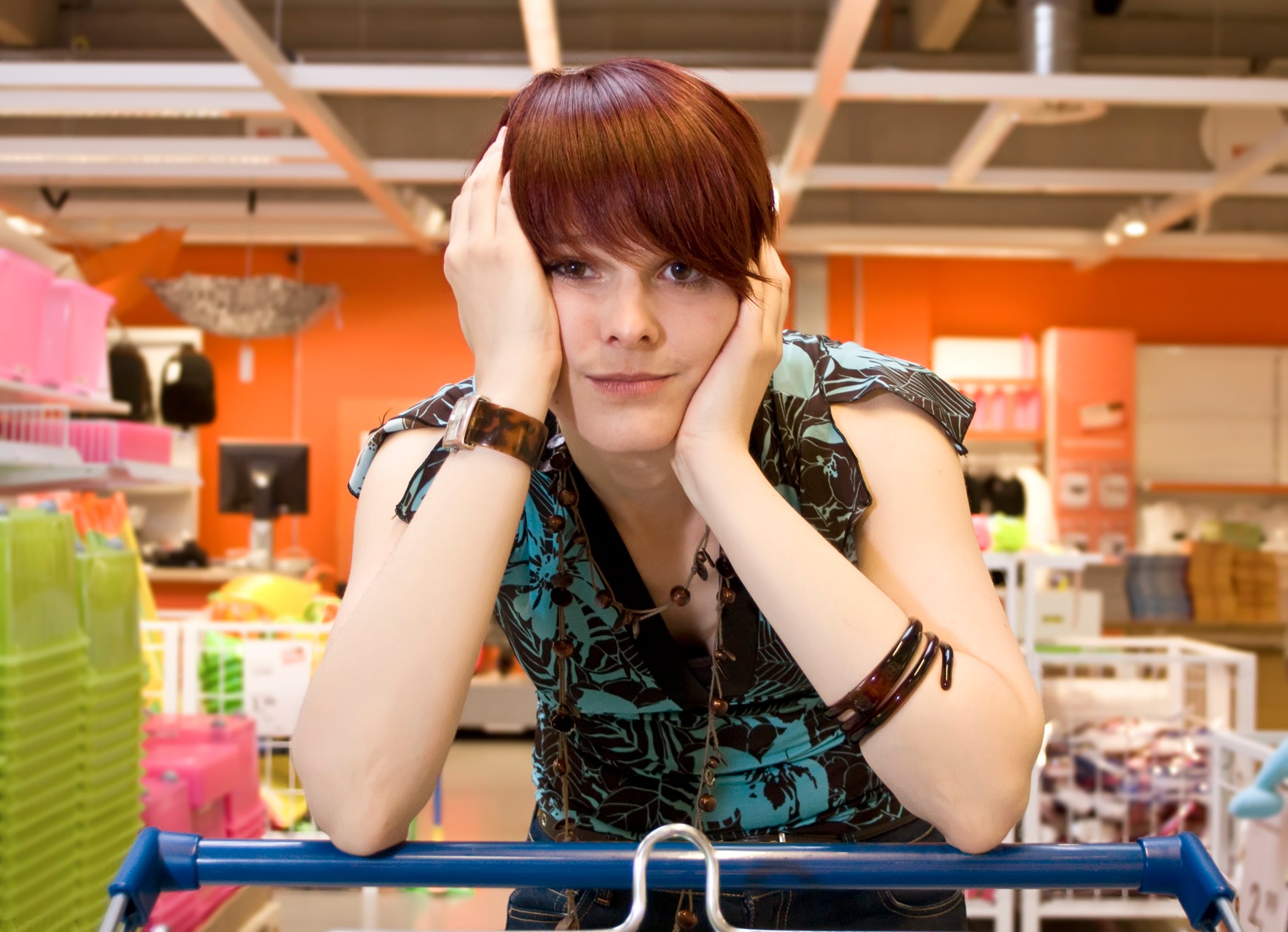 Woman resting on shopping cart in frustration