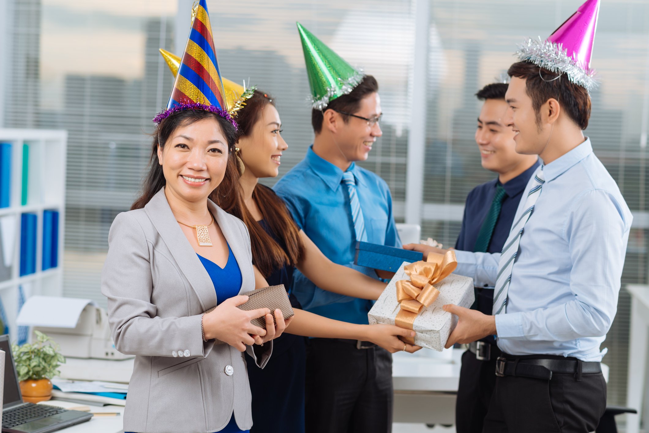 People wearing party hats exchanging gifts in an office