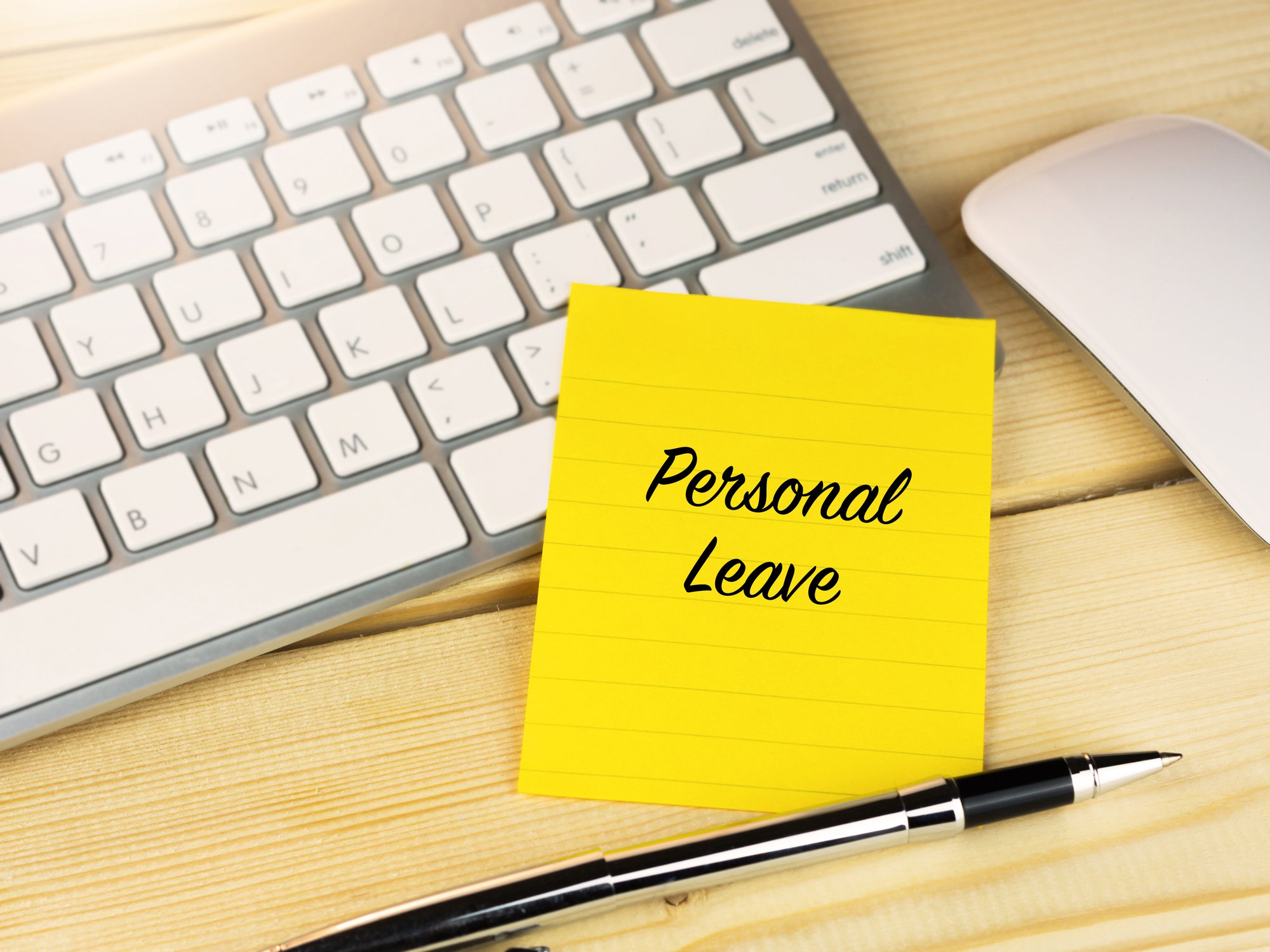 Post-it note that says personal leave on a keyboard