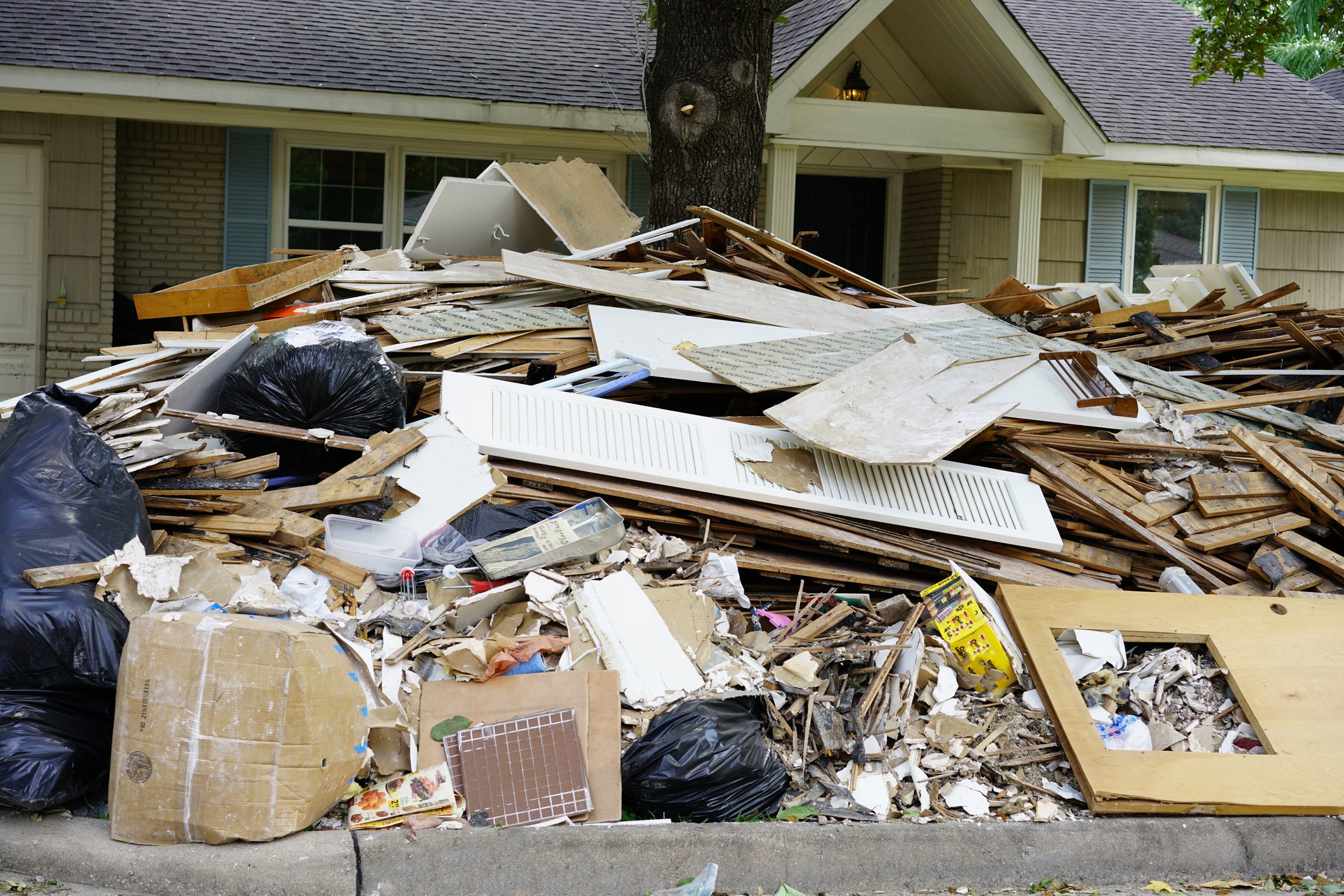 Piles of trash in front of a hurricane-damaged home