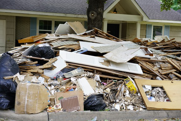 Piles of trash in front of a hurricane-damaged home