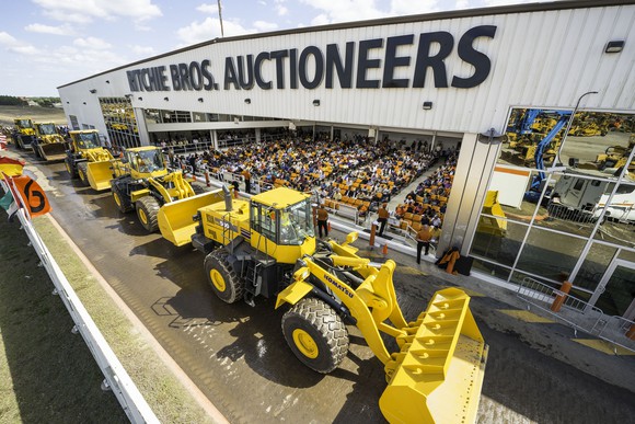 Line of heavy duty equipment in front of rows of bidders