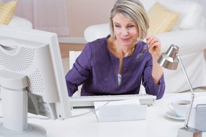 Woman looking at the screen of a desktop computer.