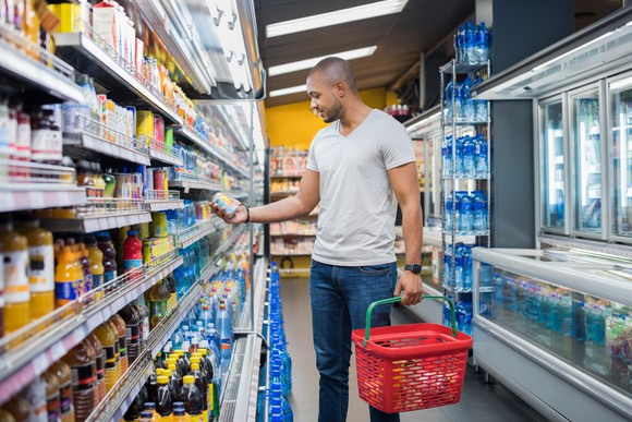 Man with half-full red basket shopping at a supermarket