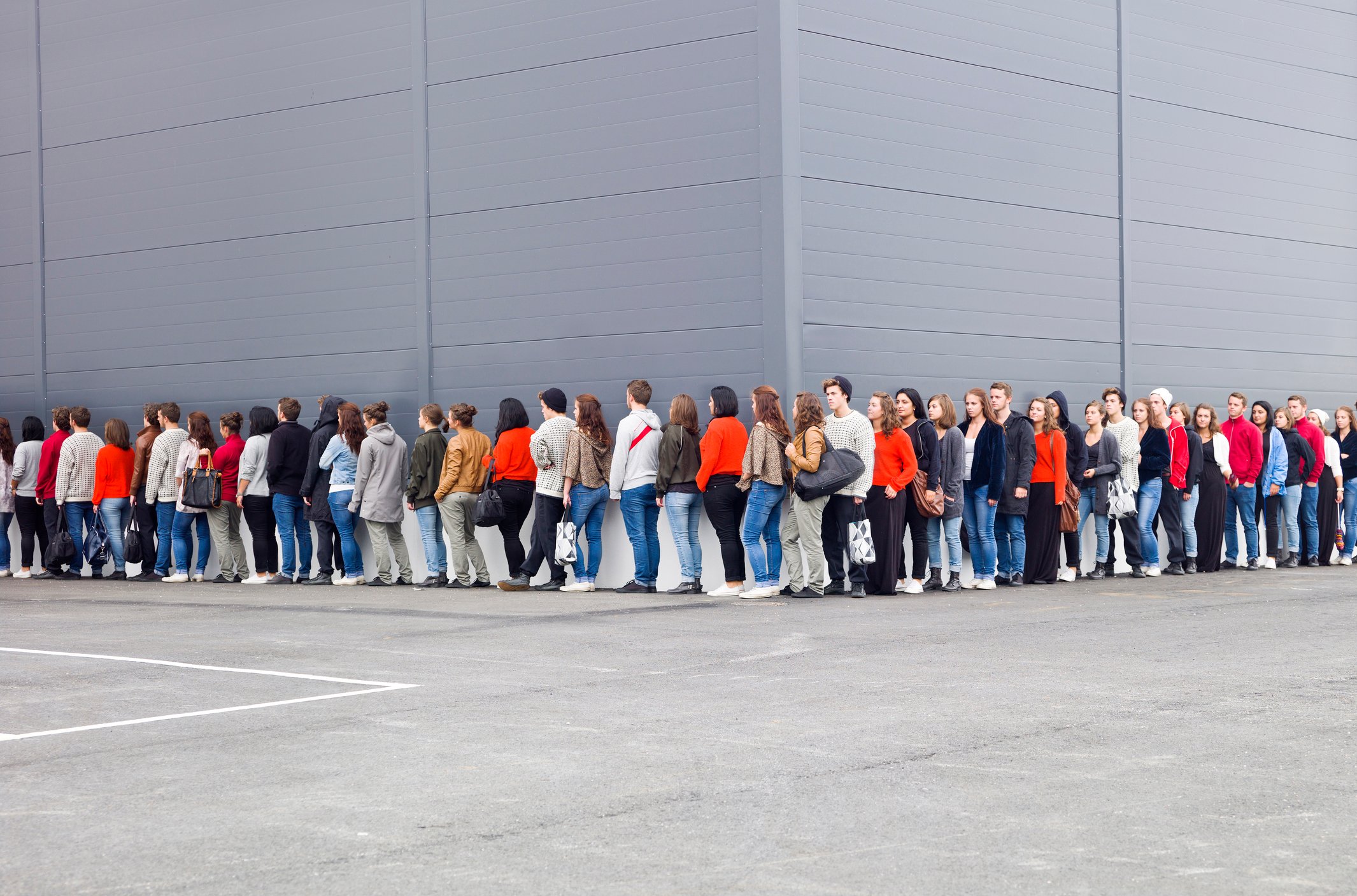 People waiting in line outside of a  store.