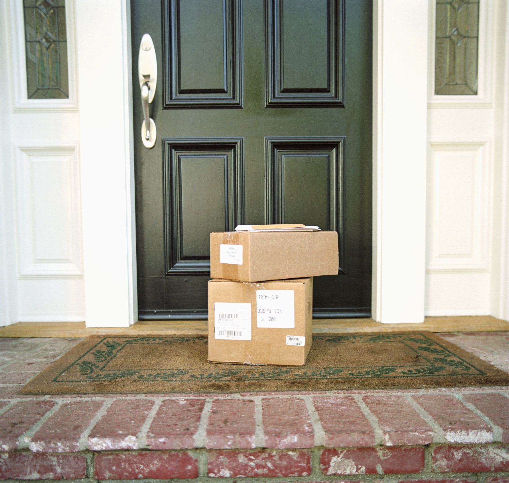 Stack of packages sitting on a front doorstep.