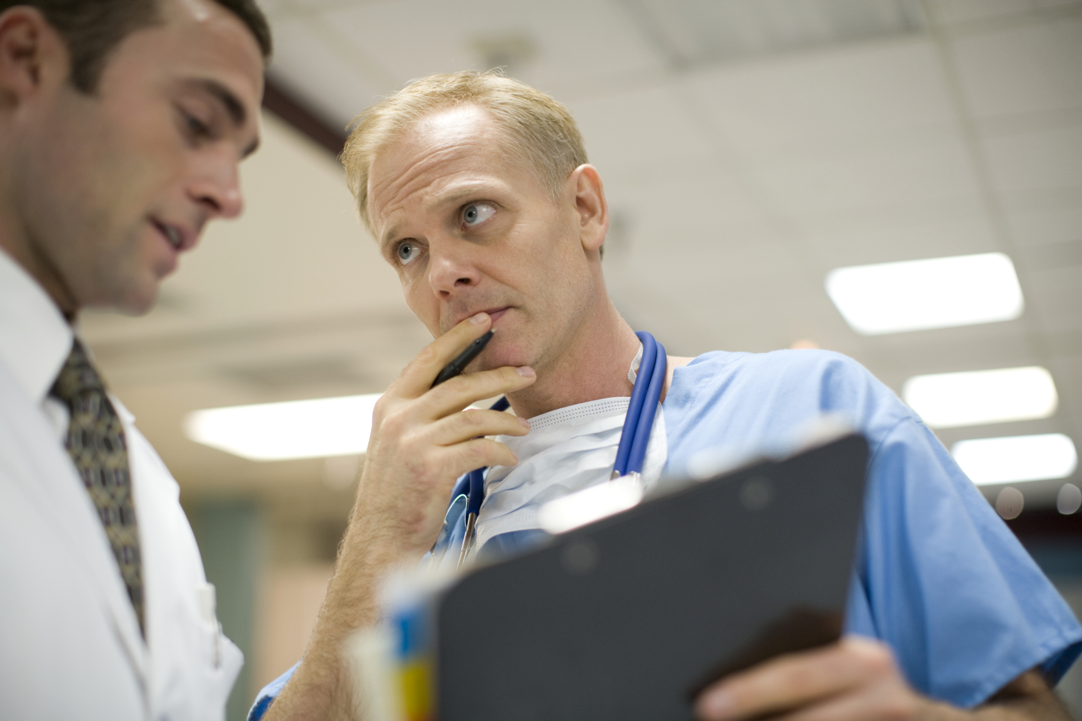 Doctors having a discussion based on information on a clipboard.  