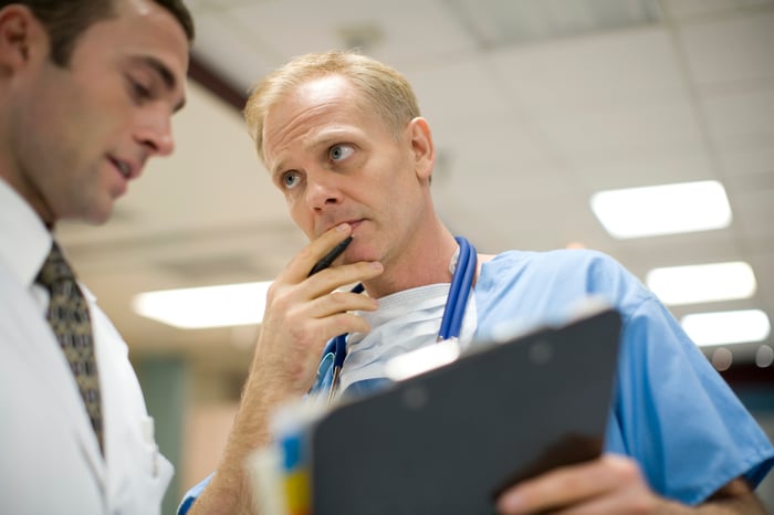 Doctors having a discussion based on information on a clipboard.  