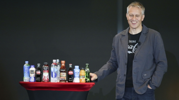 Coca-Cola CEO James Quincey standing beside an array of Coca-Cola products at the company's 2017 investor conference.